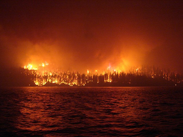 A raging wildfire on the other side of a lake.