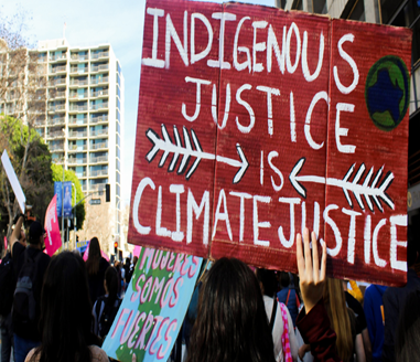 A climate protester holding a sign that says "Indigenous justice is climate justice."